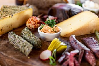Brettljause with assorted cheeses, sausage, bacon, spread, pickles and radishes served on a wooden board. | © SalzburgerLand Tourismus