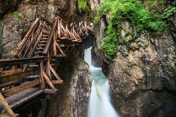 Wooden walkways lead through the rocky Sigmund Thun Gorge in Kaprun alongside a waterfall. | © Zell am See-Kaprun Tourismus