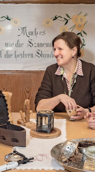 Two women sit at a table at Dietlgut with herbs, vessels and utensils for incense burning. | © Lichtfarben