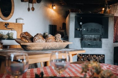 Loaves in a wooden bowl beside the oven during bread baking at Dietlgut in Hohe Tauern National Park. | © Monja Kraner
