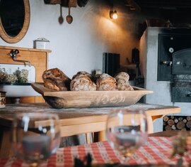Brotlaibe in einer Holzschale vor dem Backofen beim Brotbacken am Dietlgut im Nationalpark Hohe Tauern. | © Monja Kraner