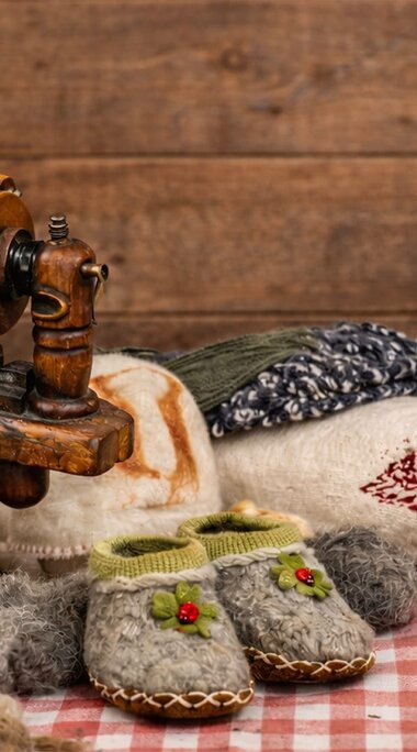 Sheep’s wool, spinning equipment, yarn, and felted and knitted handicrafts displayed on a table. | © KI generiertes Bild